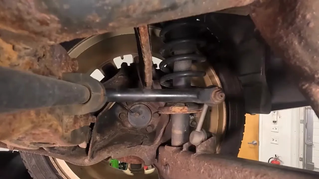 Vehicle underside showing extensive corrosion across metal components