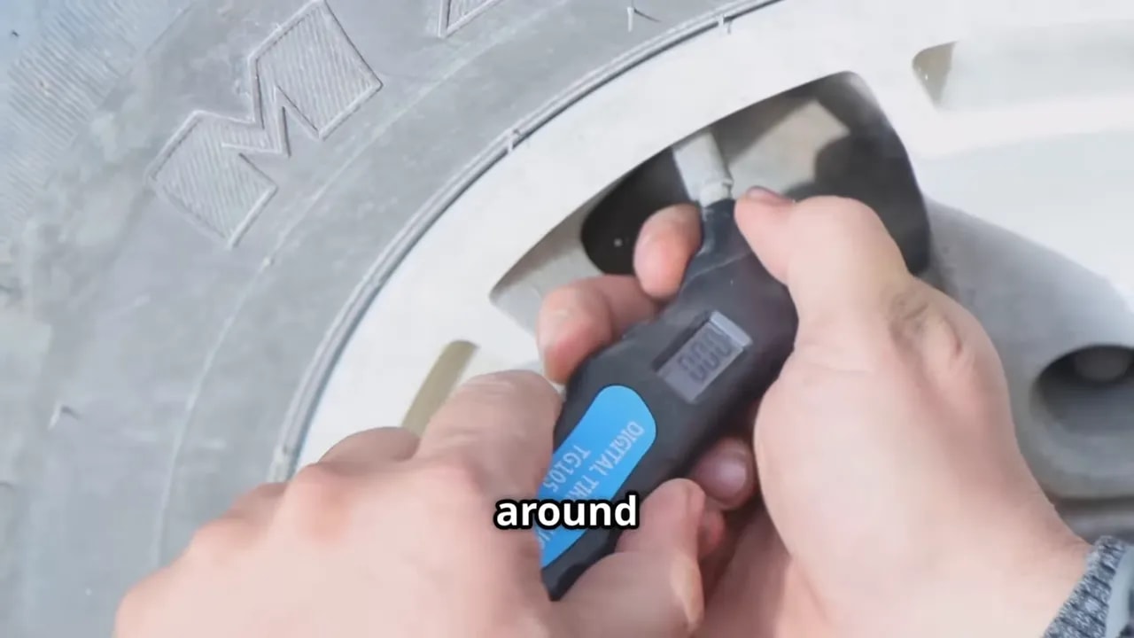Hands holding a digital tire-pressure gauge against a wheel valve