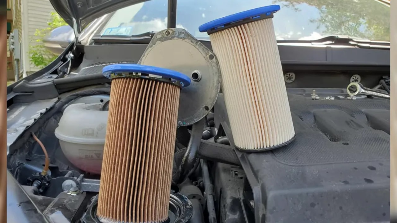 Two pleated filter cartridges held above an engine bay
