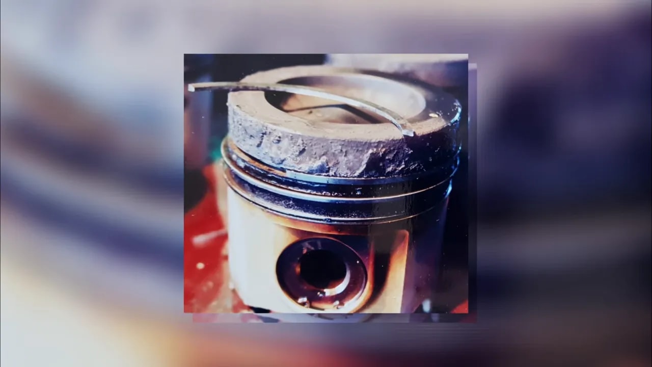 Close-up of a piston with dark deposits around the crown and ring area