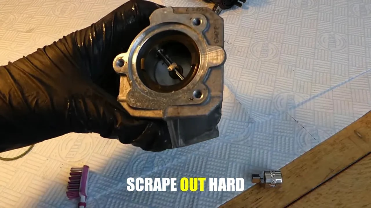 Gloved hand holding an EGR valve with its circular opening and internal mechanism visible