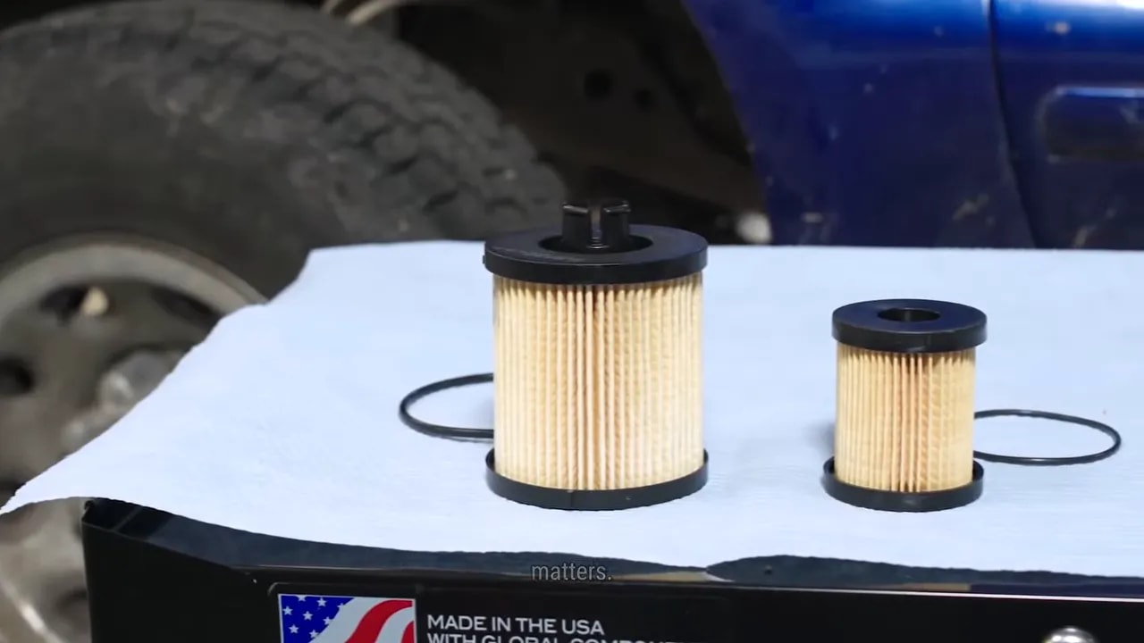 Two pleated diesel filter cartridges with sealing rings on a white surface